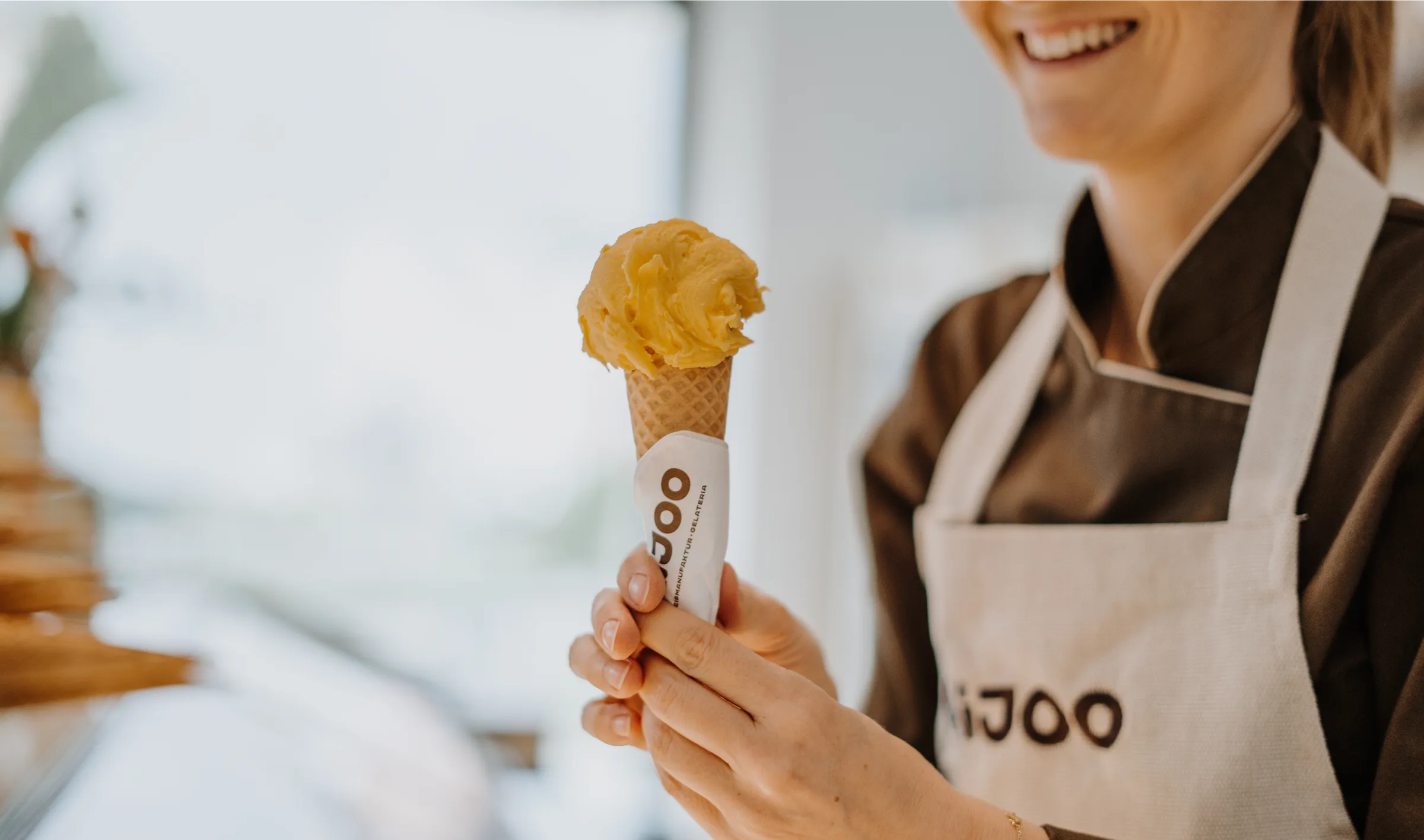 AiJOO-Mitarbeiterin hält ein Eis in der Waffel