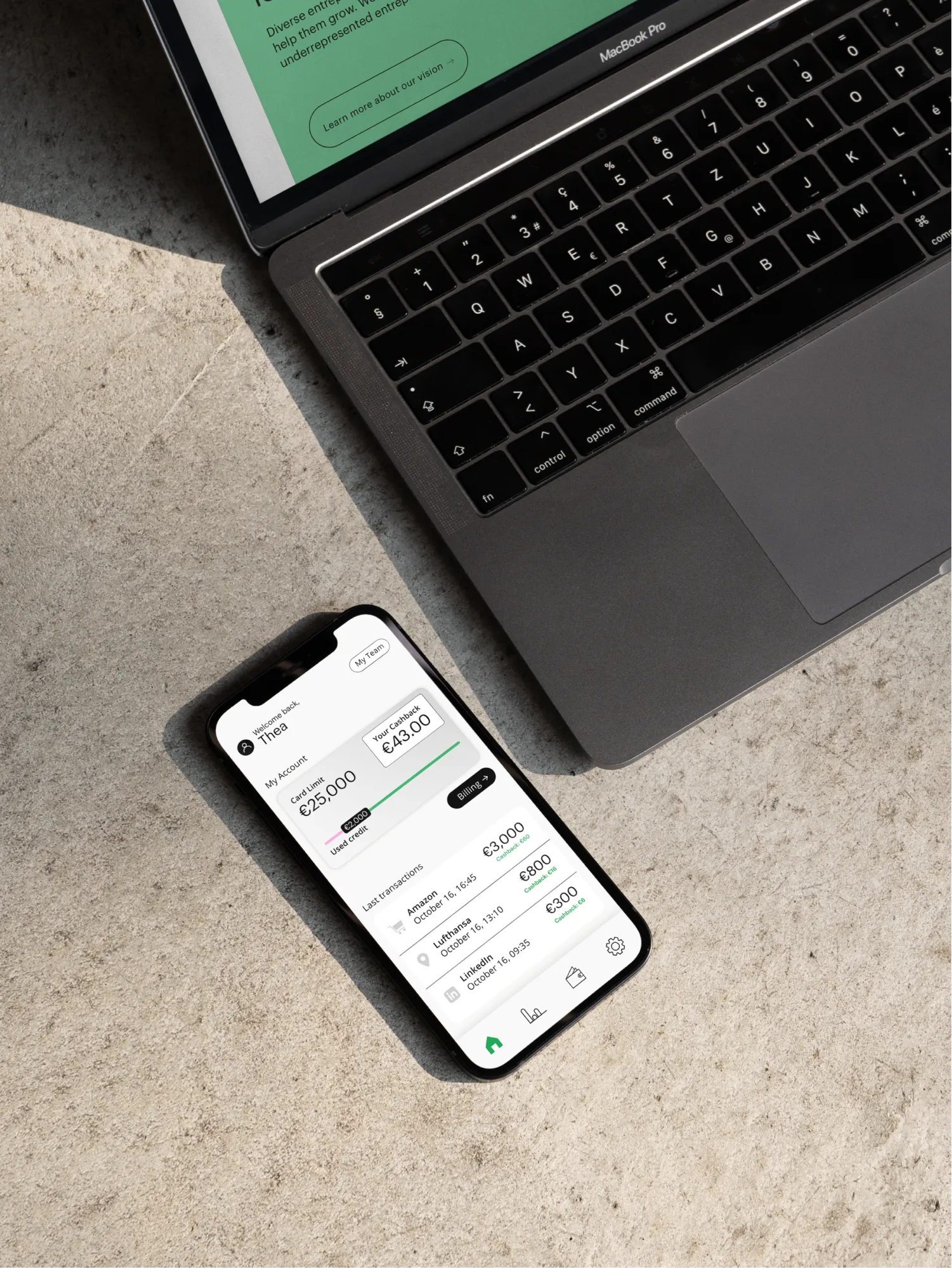 Smartphone mit der TXEYA-App neben einem MacBook auf Beton